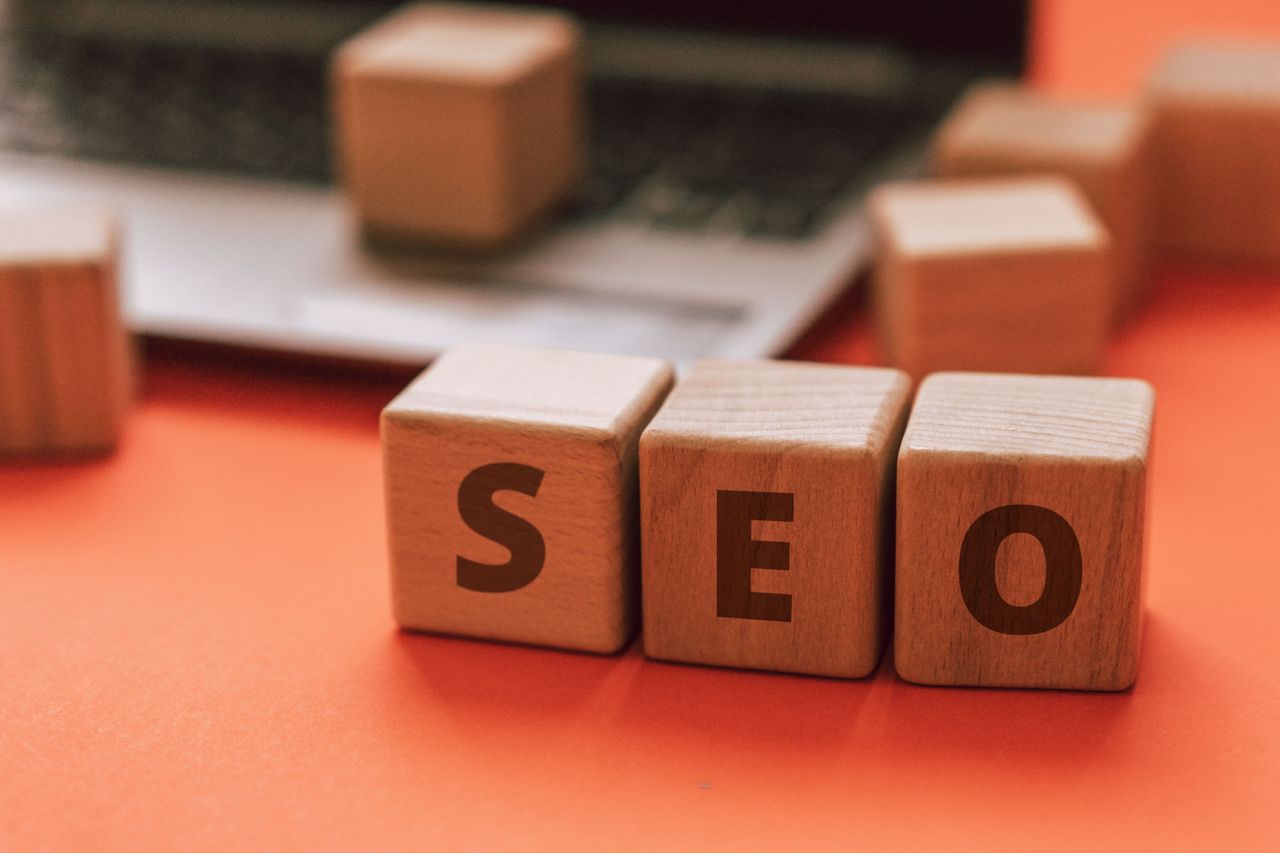 Des blocs en bois formant SEO sur le clavier d’un ordinateur portable illustrent les concepts de marketing numérique.